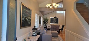 A spacious living area with a high ceiling, a dining table, and a staircase. - Capo Beach Coastal Retreat / 4 Bedrooms 4 Bath / Near Harbor & Surf (Capistrano Beach)