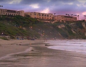 Ein Strandhotel mit einem großen Gebäude, einem Sandstrand und einer felsigen Klippe.