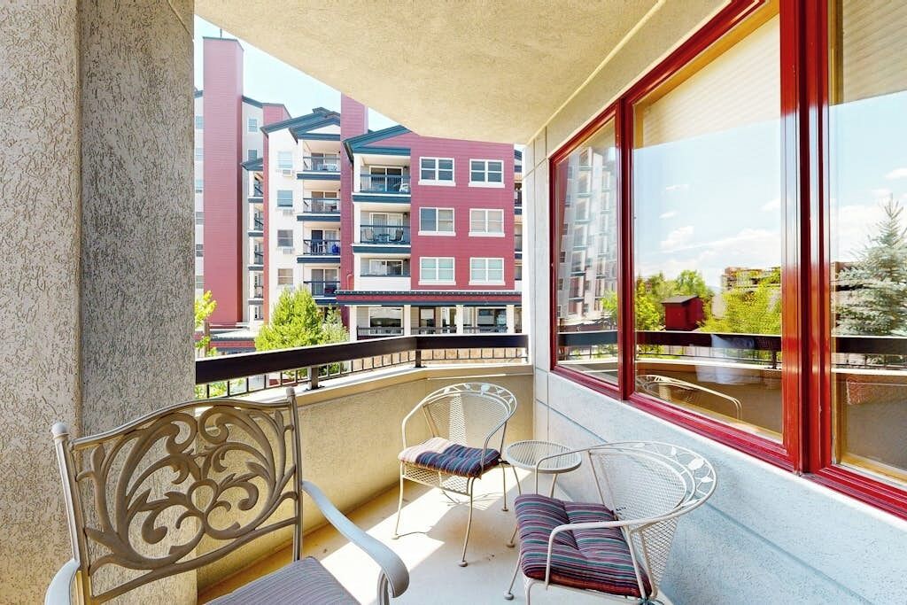 Een balkon met twee stoelen en een kleine tafel, met uitzicht op een gebouw met balkons.