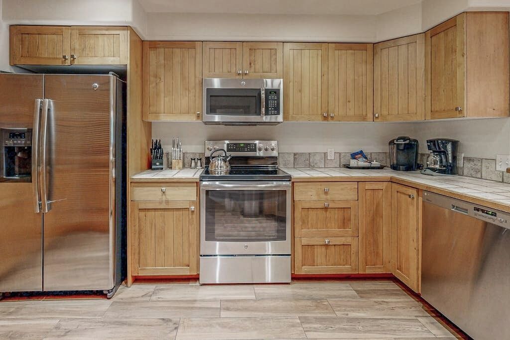 A kitchen with wooden cabinets, stainless steel appliances, a microwave, an oven, and a dishwasher.