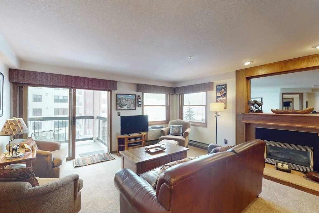 Een woonkamer met een open haard, een televisie en een balkon.