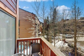 A wooden cabin with a balcony, a chair, and a view of a snowy landscape with trees. - Lovely getaway with, hot tubs & gym - close to lifts & activities (Breckenridge)