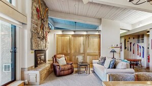 Un salon avec un mur en pierre, des lambris en bois, une cheminée, un fauteuil en cuir et un canapé.