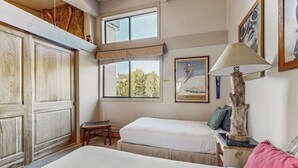 Une chambre avec deux lits, une fenêtre donnant sur un beau paysage, une lampe et un tableau encadré au mur.