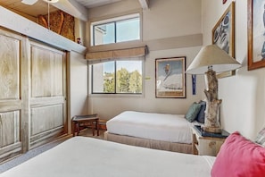A bedroom with two beds, a window with a view, a lamp, and a framed picture on the wall. - Ski-In/Out Top-Floor Condo w/Free WiFi, Fireplace, and Shared W/D, Hot Tub, Pool (Steamboat Springs)
