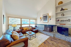 Ein Wohnzimmer mit Ledersofa, Couchtisch, Kamin und Fernseher.