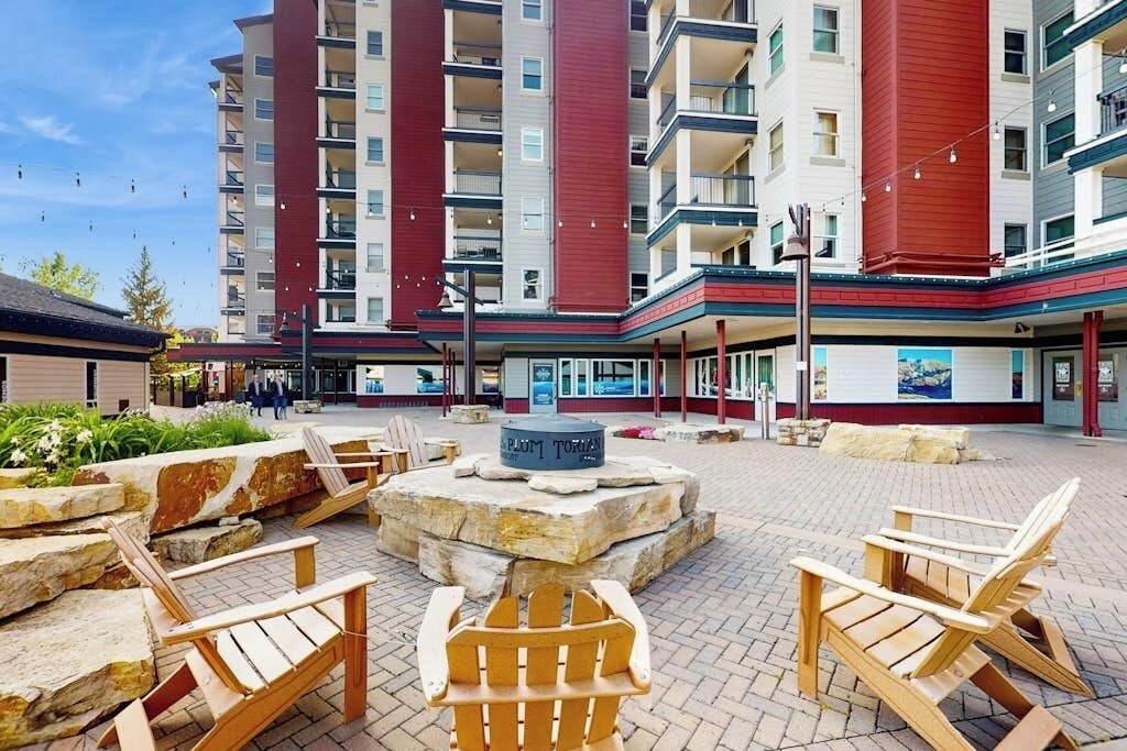 A courtyard with Adirondack chairs, a stone fountain, and a building with multiple balconies.