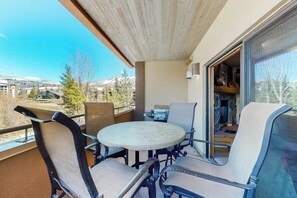 Ein Balkon mit Tisch, Stühlen, einem Grill und Blick auf die Umgebung.
