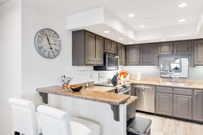 A modern kitchen with granite countertops, stainless steel appliances, and dark cabinetry. - Modern centrally located condo with pool, hot tub, gym & easy walk to lifts (Steamboat Springs)
