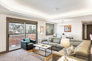 A modern living room with a sofa, armchair, coffee table, and a lamp. - Modern centrally located condo with pool, hot tub, gym & easy walk to lifts (Steamboat Springs)