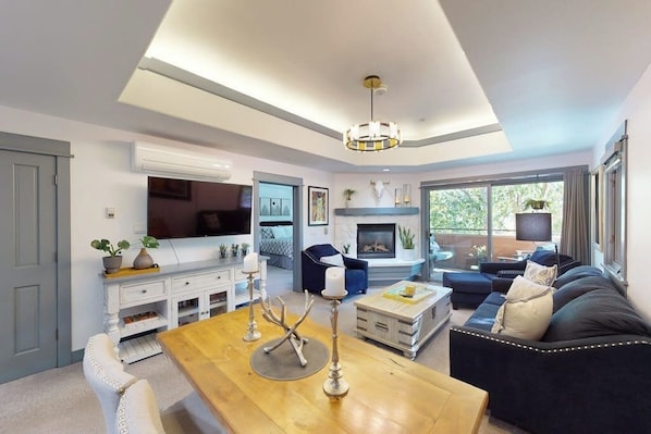 Ein modernes Wohnzimmer mit Fernseher, Kamin, Sofa und Essbereich.