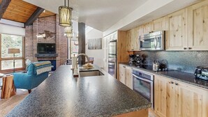 Una cocina moderna con encimeras de granito, armarios de madera, horno empotrado y una isla grande con pileta.
