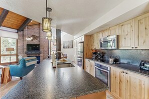 A modern kitchen with granite countertops, wooden cabinets, a built-in oven, and a large island with a sink. - Beautiful mountain condo with balcony, deck, hot tub & pool & washer/dryer (Steamboat Springs)