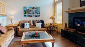 Un salon comprenant un canapé, une table basse, une cheminée et des œuvres d’art murales.