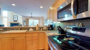 Une cuisine moderne avec des meubles en bois, un four à micro-ondes en acier inoxydable et une plaque de cuisson à induction.