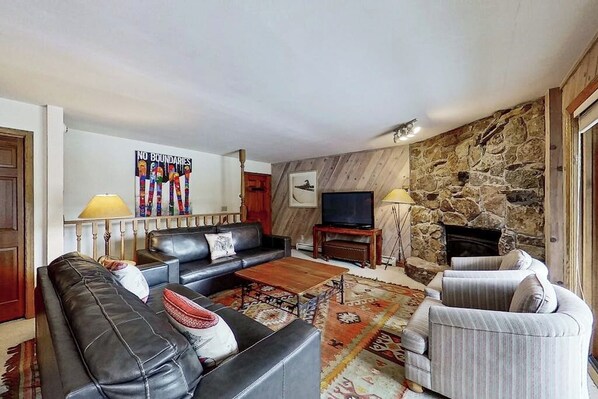 Ein Wohnzimmer mit Steinwand, einer Couch, einem Couchtisch und einem Fernseher.
