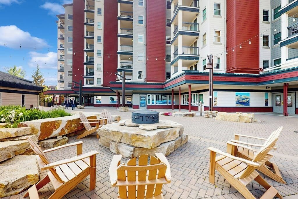 A courtyard with outdoor seating, a fire pit, and a building with balconies.