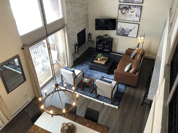 A modern living room with a fireplace, a television, and artwork on the wall. - Remodeled condo with mountain views, balcony, & hot tub access (Steamboat Springs)