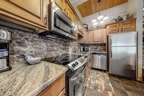 Eine Küche mit Granit Arbeitsplatten, einem eingebauten Backofen, einem Edelstahlkühlschrank und Holzschränken.