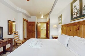 Ein Hotelzimmer mit Bett, Schreibtisch, Stuhl, Fernseher und einem durchgehenden Türbogen einsehbaren Badezimmer.