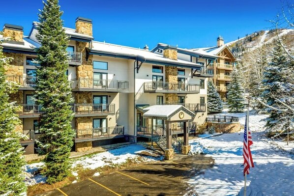 A multi-story hotel with balconies, a covered entrance, and a snow-covered landscape. - Ski-In/Ski-Out Condo w/ Gas Fireplace, Balcony & Shared Hot Tub (Steamboat Springs)