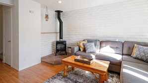 Ein Wohnzimmer mit Sofa, Couchtisch, Kamin und einer Pendelleuchte.