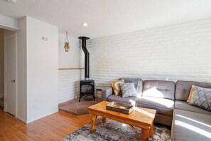 Ein Wohnzimmer mit Sofa, Couchtisch, Kamin und einer Pendelleuchte.