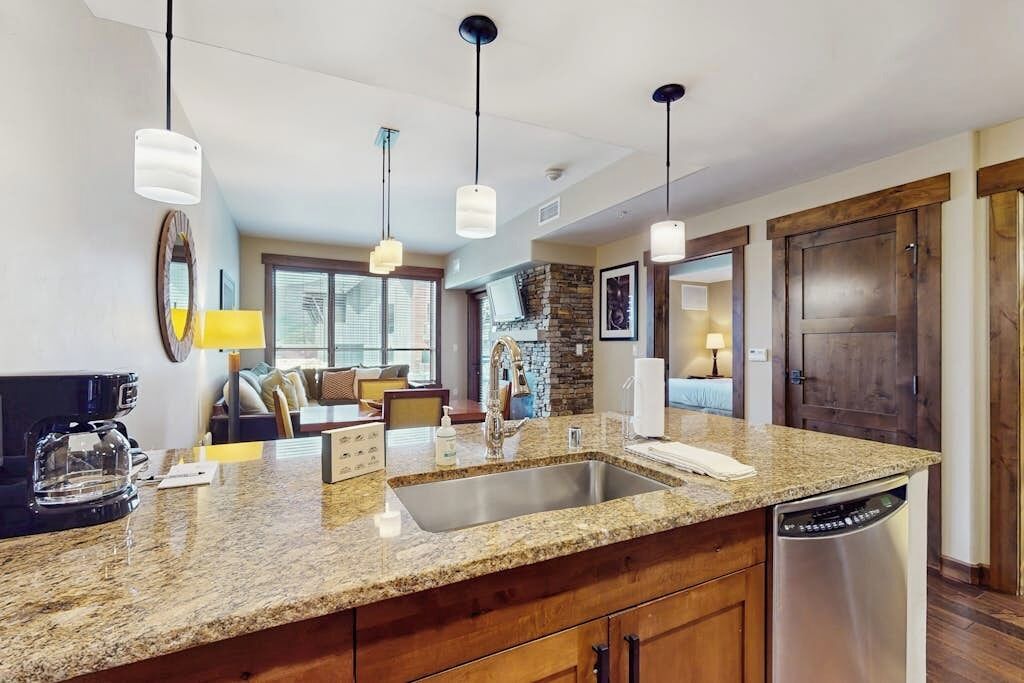 A modern kitchen with granite countertops, stainless steel appliances, and pendant lighting.