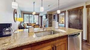 Una cocina moderna con encimeras de granito, electrodomésticos de acero inoxidable e iluminación colgante.