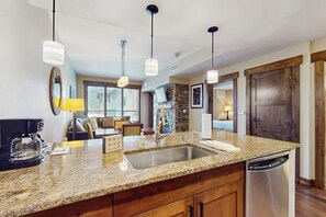 A modern kitchen with granite countertops, stainless steel appliances, and pendant lighting. - High-End Condo w/ WiFi, AC, Fireplace & Shared Pool/Hot Tubs/Gym - Walk to Lifts (Steamboat Springs)