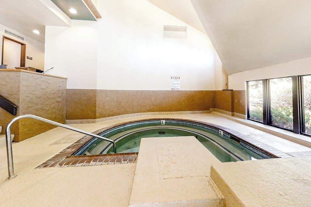 Una piscina interior con diseño curvo, una recepción y un amplio ventanal que ofrece vistas al exterior.