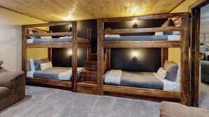 Una habitación con literas, una escalera y un sofá.