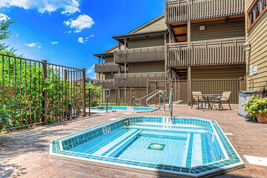 A pool area with a 3 FT depth marker, a wooden fence, and a building with balconies.