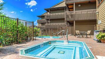 A pool area with a 3 FT depth marker, a wooden fence, and a building with balconies.