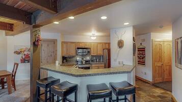A kitchen with wooden cabinets, a granite countertop, and a central island with bar stools.
