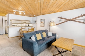 Ein gemütlicher Wohnbereich mit einem blauen Sofa, einem Holztisch und einem Essbereich mit Tisch und Stühlen.
