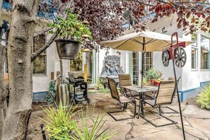 Eine Terrasse mit Tisch und Stühlen, einem hängenden Pflanzgefäß und einer Zierwand.