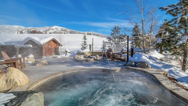 Een warmwaterbronnengebied met een houten hut, lounge stoelen en een besneeerd landschap.