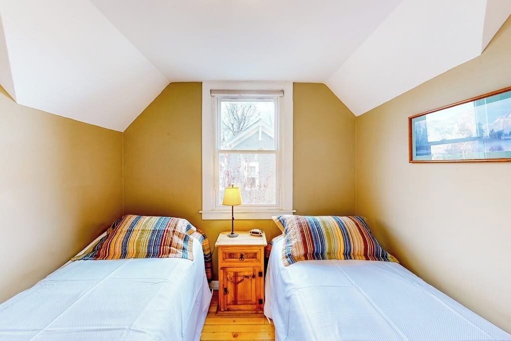 A small room with two beds, a window, and a lamp.