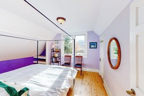 A bedroom with a bed, a window, a chair, a bookshelf, and a door. - Restored downtown home with front porch, mountain views, & washer/dryer (Steamboat Springs)