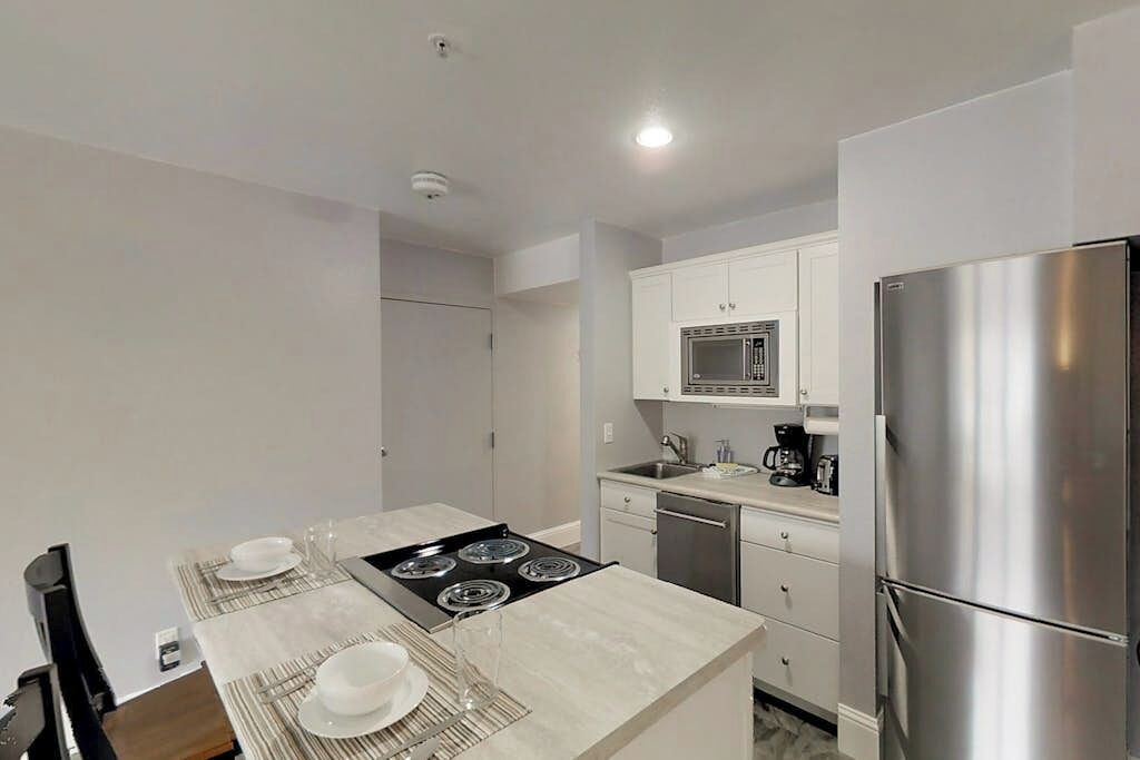 A modern kitchen with a central island, stainless steel appliances, and white cabinetry.