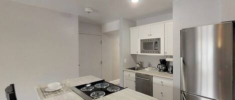 A modern kitchen with a central island, stainless steel appliances, and white cabinetry.