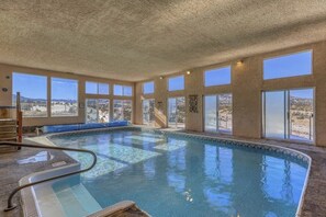 Ein Hallenbad mit großen Fenstern, einer Rutsche und Blick auf die Wüstenlandschaft.