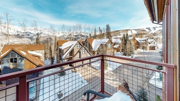 Ein Balkon mit Blick auf ein verschneites Dorf und Berge.