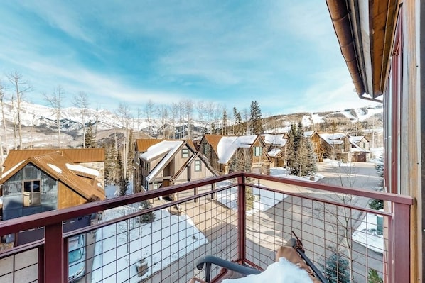 Ein Balkon mit Blick auf ein verschneites Dorf und Berge.
