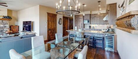Una cocina moderna con una mesa de comedor de vidrio, armarios de madera y una isla central.