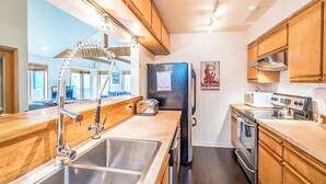 Una cucina moderna con mobili in legno, elettrodomestici in acciaio inossidabile, un lavello doppio e un frigorifero.