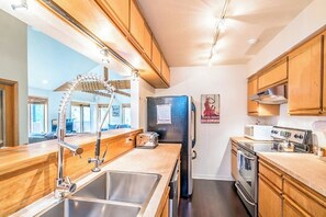 Eine moderne Küche mit Holzausbau, Edelstahlgeräten, einer Spüle und einem Kühlschrank.