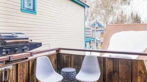 Ein Balkon mit Grill, zwei Stühlen und einem Holenzaun.