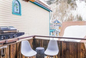 Ein Balkon mit Grill, zwei Stühlen und einem Holenzaun.